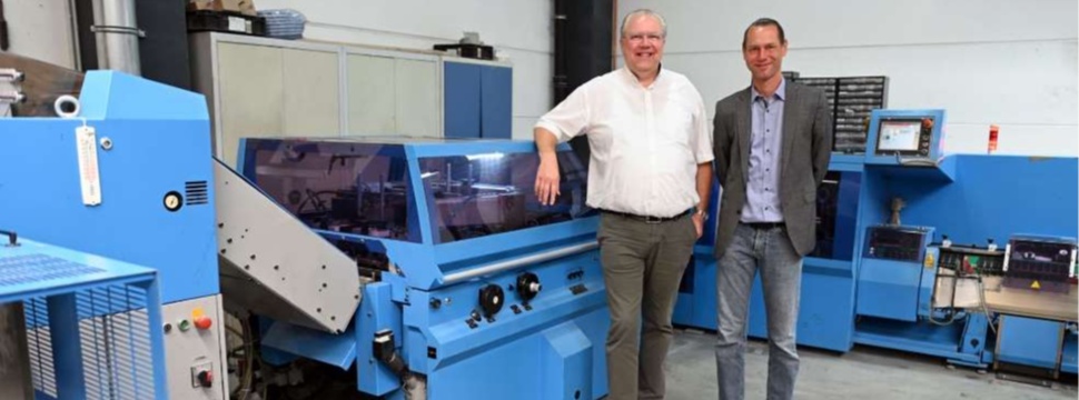 Thomas Klein-Bösing (left/in front of the Primera C130 saddle stitcher): "For us as a magazine specialist, high machine availability is particularly important." On the right, the second Managing Director of D+L Printpartner, Dirk Reichenberg.