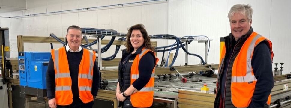 Three people in front of a gluing machine