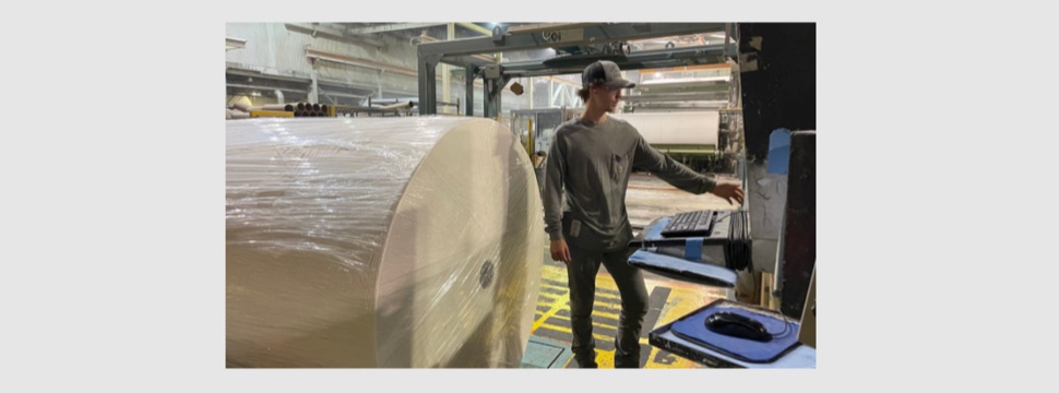 A Georgia-Pacific employee stands in front of new equipment that will make paper for Angel Soft® and strategic private label bath tissue.